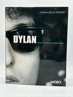 Front cover of the book showing a close-up of Bob Dylan with sunglasses and the title 'DYLAN, Visions, Portraits and Back Pages' with foreword by Bono and Mojo brand.
