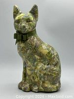 Green sitting cat figurine shown at side angle displaying glossy leafy pattern and green ribbon bow