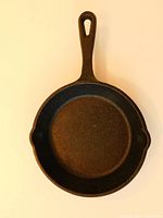Top view of the cast iron skillet showing the round cooking surface, two spouts, and handle