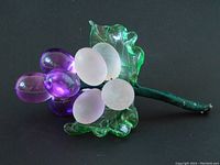 Full view of vintage grape cluster with translucent purple grapes, frosted white grapes, and green glass leaves on a green string wrapped stem.