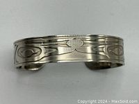 Close-up front view of pewter cuff bracelet showing engraved Raven design motifs with symmetrical abstract elements.