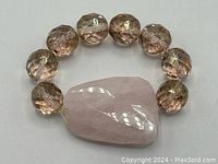 Stretch bracelet with large faceted rose quartz bead and multifaceted light pink beads on elastic band, displayed flat.