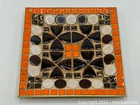 Top-down view of square mosaic tile ashtray showing geometric tile pattern with brown, orange, cream, and black tiles