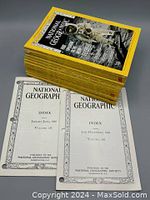 Stack of twelve 1969 National Geographic magazines with yellow borders and an astronaut cover issue on top, accompanied by two index books for 1969 published by the National Geographic Society.