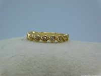 Close-up of gold tone braid twist eternity band ring showing clear crystals embedded between the braid pattern.