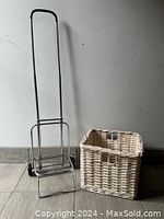 Metal collapsible carrier and white wicker cube side by side against wall