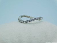 Silver-tone modern wave shaped ring with clear crystals in a half eternity style, shown on white background.