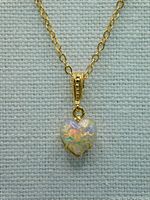Close-up of the heart-shaped synthetic opalite pendant suspended from a gold-toned chain showing the details of the stone and setting.