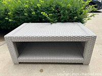 Front-facing photo showing the open shelf space beneath the top surface and woven rattan texture on the sides.