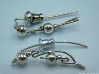 Close-up image of the pair of sterling silver earrings showing twisted wire design and two sizes of silver balls. Included are two earring backings shown beside the earrings.