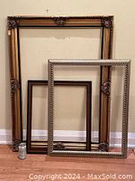 Three decorative wood frames arranged leaning against a wall, showing size and color differences, with a soda can for scale.