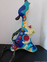 Photo of dog-shaped guitar toy showing colorful buttons, bone-shaped whammy bar, and strap.