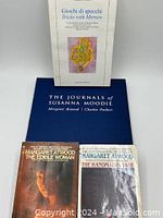 Front view of the four books: 'Giochi di Specchi, Tricks with Mirrors' with colorful illustration on white cover, 'The Journals of Susanna Moodie' large blue hardcover, and paperbacks 'The Handmaid's Tale' and 'The Edible Woman'.