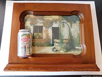Frontal view of vintage wooden frame holding the garden print with a can for scale.