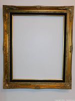 Full view of the ornate vintage Spanish Baroque style wood frame with gold gilt finish and black inset border, empty center area.