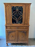 Full frontal view of vintage oak cabinet showing upper glass door with decorative wood lattice, velvet-lined drawer, and lower double doors with carved details.