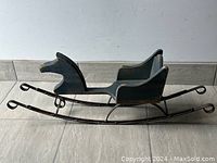 Full view of the vintage dark blue wooden rocking horse sleigh/cart showing the shape and condition.