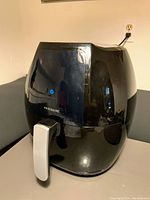 Front angled view of the black Frigidaire air fryer showing the device with silver handle and glossy finish.