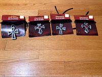 Four new gothic necklaces with plastic cross pendants displayed on wooden floor, still in packaging labeled 'Gothic Necklace Collier Gothique'.