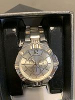 Close-up of the silver metal analog watch with subdials and decorative stones on bezel and band.