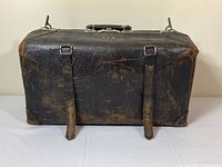 Full view of dark brown leather 1940's Carson Quality Luggage travel bag showing wear, two leather straps on front, reinforced corners.
