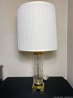 Full view of lamp with white pleated fabric shade, showing overall height and design