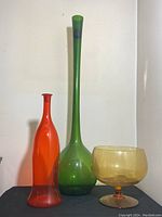 Photo showing all three glass decor items together: red vase, green bottle, and amber bowl.