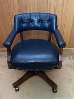 Front view of chair showing tufted backrest, wood frame and leather seat