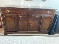 Full front view of walnut sideboard showing all doors closed and brass ring pull handles.