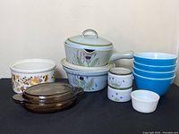 Photo of entire dish lot showing all items including floral pots, blue Pyrex bowls, and white dish.