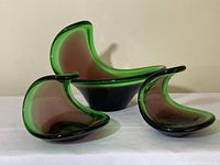 Front view of three MCM coquilles-style glass decor pieces showing green outer color and brown interior.