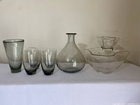 Full lot showing four smoke glass drinking glasses, a 9-inch decanter, 7-inch vase, and clear glass chip and dip set