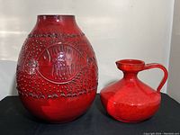 Pair of vases side by side on black surface against white background