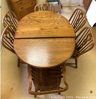Overhead view of oval oak dining table with two leaves inserted and six chairs positioned around it