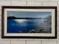 Full view of framed acrylic painting on white brick wall