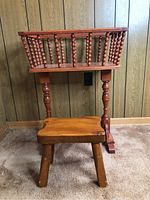 Photo showing maple flower box and wooden stool with spindle design flower box on top, against wood panel wall.