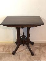 Full front view of Victorian walnut parlor table showing rectangular top, central pedestal and four legs on casters.
