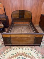 Front view of full wooden bed frame showing headboard, footboard, and metal springs inside the frame.