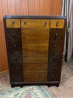 Front view of vintage wood highboy dresser with multiple drawers and decorative pulls.