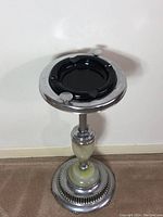 Full view of vintage standing ashtray from top angle showing black metal tray insert and chrome edge.