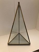 Glass triangular pyramid display showing mirrored base and brass framing.