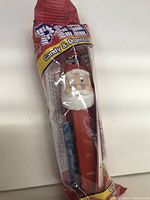 Photo of unopened Santa PEZ candy dispenser still in original packaging showing Santa head design and candy contents inside.