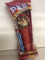 Photo of a new Elf PEZ candy dispenser in original sealed packaging with candy stick included.