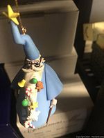 Photo of the Disney Merlin Christmas tree ornament in a blue robe holding a wand with a star, decorated with a garland of Christmas items.