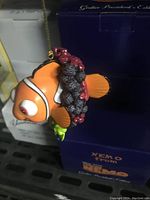 Photo shows vintage Finding Nemo Christmas tree ornament in original dark blue box, with Nemo figure featuring coral-like wrapping and attached hanging string.