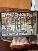 Framed painting on chair against wood floor, full front view