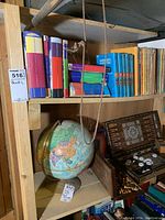 Wooden shelves filled with various books including Dr. Seuss, Hardy Boys, and other vintage titles. Lower shelf shows a globe and a decorative box.