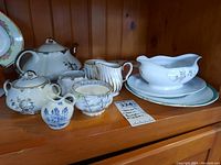 Various china tea ware items including teapots, cups, creamer, sugar bowl, and serving dishes with floral designs.