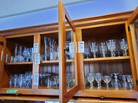 Wide angle view of multiple glass shelves filled with crystal stemware including wine glasses and other types from Cross & Olive brand.