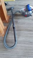 Dyson Big Ball Extra vacuum cleaner with hose and wand; unit laying on laminate floor, showing main body and hose.